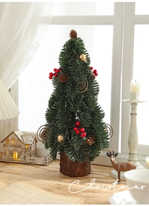 Close-up of a mini snowy Christmas tree with red berries and a natural wood base