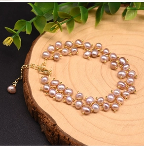 Detailed close-up of multilayer pink freshwater pearl bracelet on a rustic wood base