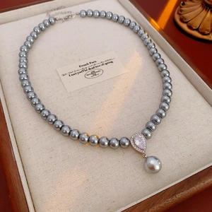 Detail of grey pearl necklace with a large teardrop zircon pendant on a linen tray