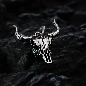 Macro shot of vintage silver bull skull pendant on dark rock background with chain