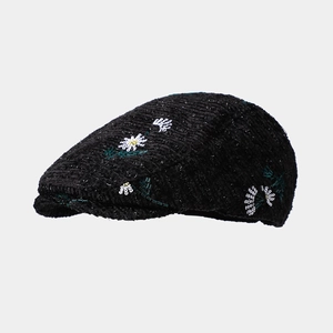 Detail of floral embroidery on black corduroy newsboy cap showing texture and stitching
