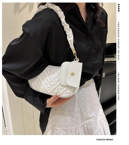 Close-up of quilted white faux leather shoulder bag with gold hardware and ruched strap