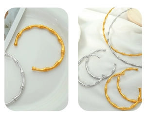 Detail showing gold and silver bamboo-shaped open bangles on silk and white plate