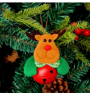 Detail of plush reindeer Christmas bell ornament hanging on a festive green pine tree