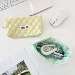 Close-up of quilted fabric pencil cases in pastel yellow and mint with zipper closure