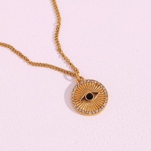 Detail of 18K gold plated evil eye coin pendant with black bead and white crystals