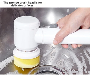 Electric handheld scrubber with yellow sponge head cleaning a soapy stainless steel sink
