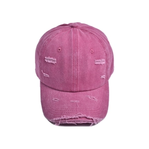 Detailed macro view of distressed rose red cotton baseball cap with frayed edges