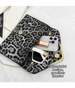 Detail view of leopard print envelope bag interior with gold chain strap and accessories