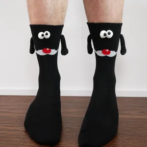 Close-up of black creative mid-calf magnetic holding hands socks with cute 3D eyes