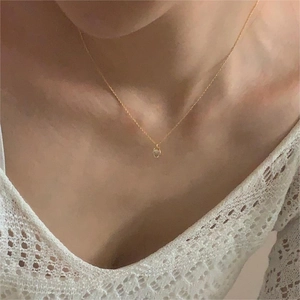 Detailed close-up of a minimalist gold pendant necklace featuring a round clear gemstone