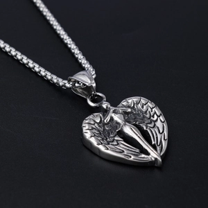 Detailed view of silver heart pendant with embossed angel wings on a black background