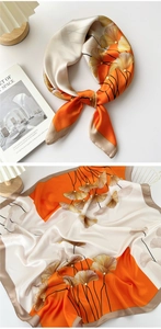 Detail of silk scarf with orange and gold ginkgo leaf print and satin finish