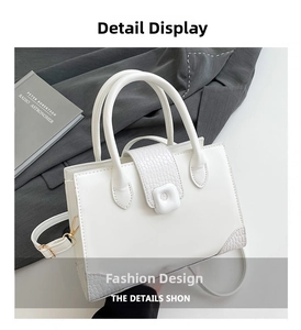 Detail view of white tote bag showing crocodile texture stitching and metal buckle