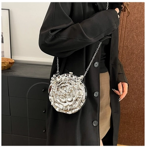 Detail of rose-shaped silver PVC clutch with metallic finish and delicate chain strap