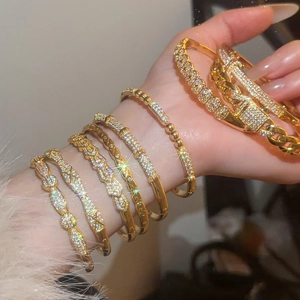 Detailed view of layered gold-plated bracelets featuring cubic zirconia on wrist