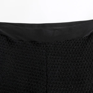 Close-up of black crochet knit fabric with wavy hollow texture and elastic waistband