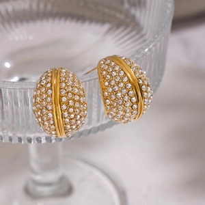 Elegant gold drop earrings with clear rhinestones on glass stand with marble background