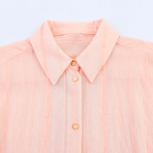 Detail of pink striped shirt collar featuring elegant gold buttons and lapel design