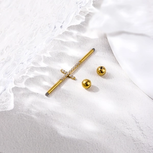 Piercing industriel doré en acier inoxydable avec croix en cristal sur fond blanc