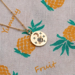 Macro detail of gold celestial pendant necklace featuring colorful zircon stars and moon