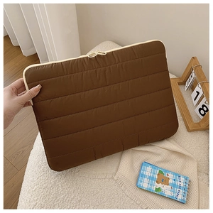 Detail of a dark brown quilted laptop sleeve with thick padding and secure zipper closure