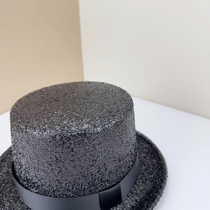 Détail d'un chapeau haut-de-forme noir scintillant avec paillettes et ruban gros-grain