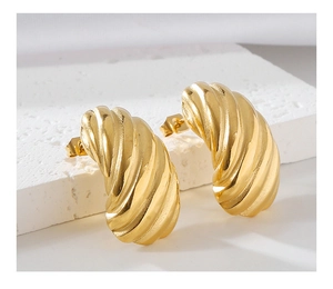Macro view of gold stainless steel stud earrings with elegant croissant spiral texture