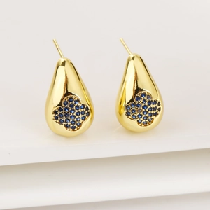 Detailed close-up of golden teardrop earrings with a blue zircon four-leaf clover motif