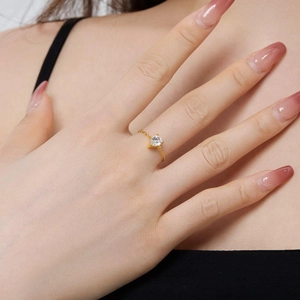 Detail of adjustable gold chain ring featuring a teardrop zircon worn by a model