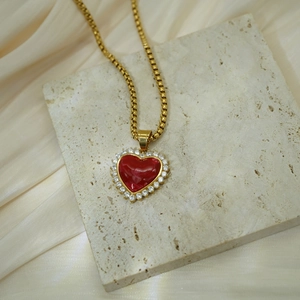 Detail of red heart gemstone necklace with 18K gold stainless steel on textured stone