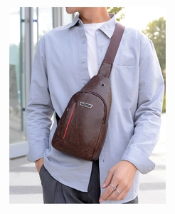 Detail of dark brown PU leather chest bag with red stripe and metal brand plaque