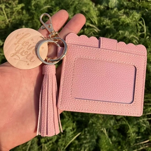 Detailed view of pink lychee leather card holder with tassel and engraved wooden charm