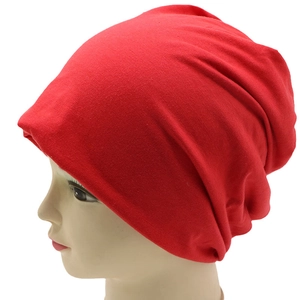 Close-up of bright red slouchy beanie showing knitted cotton texture and elastic fit