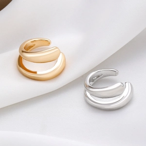Detalle de pendientes de doble capa en oro y plata sobre tela de seda blanca pura