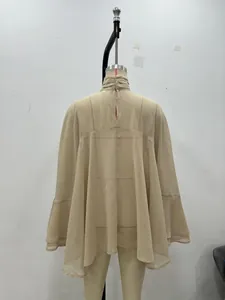 Détail de blouse en georgette beige avec col montant à volants et manches poncho