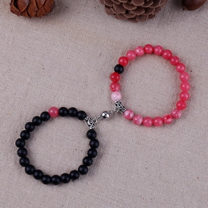 Detail of 8mm natural stone couple bracelets with magnetic heart charm on linen background