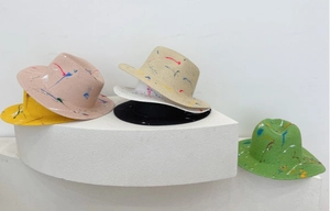 Artistic graffiti straw fedora hats with colorful spray paint on geometric white stands