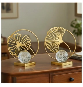 Close-up of golden ginkgo leaf metal stand with bubble crystal ball on wooden desk