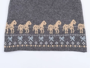 Detail of grey knit fabric with yellow pony and blue bow jacquard pattern