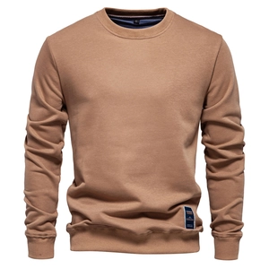 Detailed close-up of ribbed cuffs and hem on a solid brown men's crewneck sweatshirt