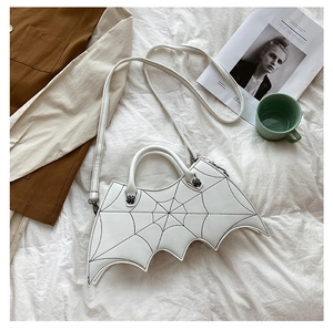 Flat lay of white bat-shaped PU leather crossbody bag with spider web patterns
