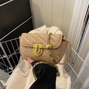Chic beige V-quilted crossbody bag with gold chain and ball charm on white blazer