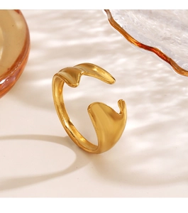 Macro detail of golden irregular wave open ring against amber glassware background