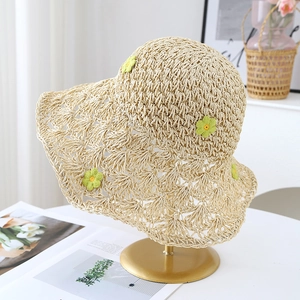 Détail d'un chapeau de paille beige avec fleurs au crochet et texture tissée ajourée