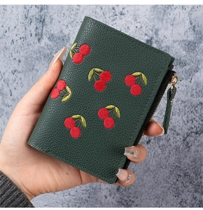 Close-up of dark green lychee grain leather wallet with red cherry embroidery detail