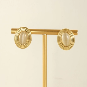 Detailed view of vintage oval gold earrings with natural stone on a metal stand
