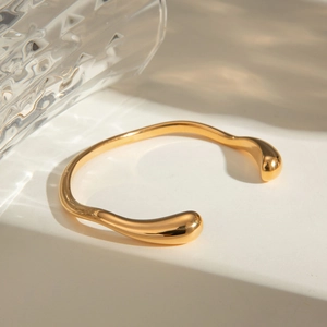 Irregular 18k gold plated stainless steel open bangle with a wave-like flowing design