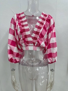 Detail of pink plaid V-neck crop top with ruffled trim and elastic puff sleeves