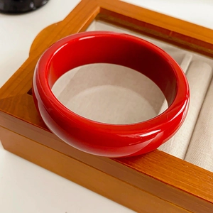 Gros plan d'un jonc rond en résine rouge brillant sur un écrin à bijoux en bois massif